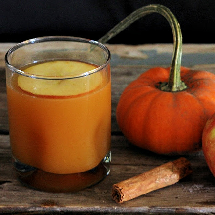 Bourbon Apple Pumpkin Cocktail in a glass with a mini pumpkin and cinnamon stick 